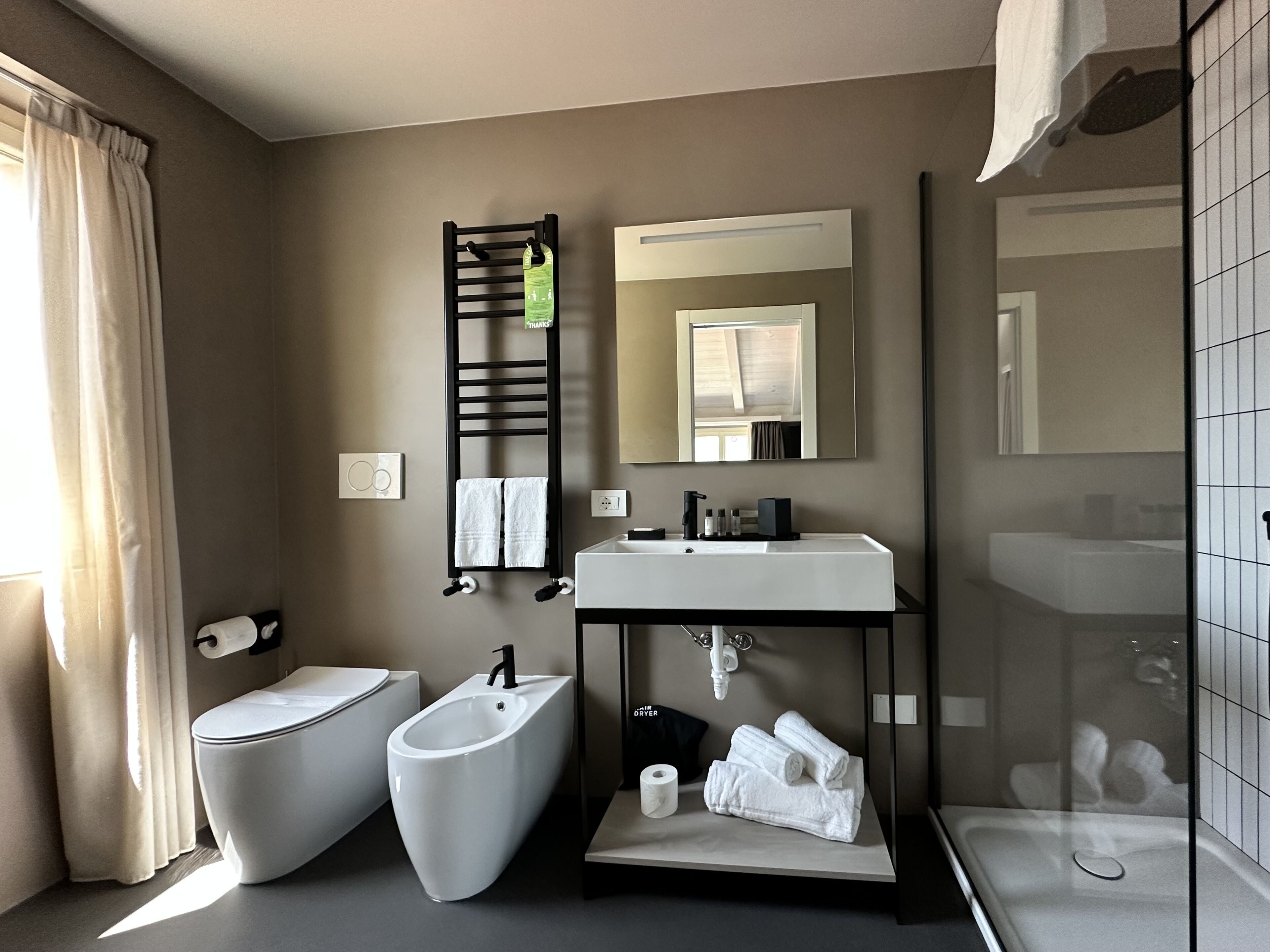 A modern bathroom with a bidet, toilet, sink, and a glass-enclosed shower.