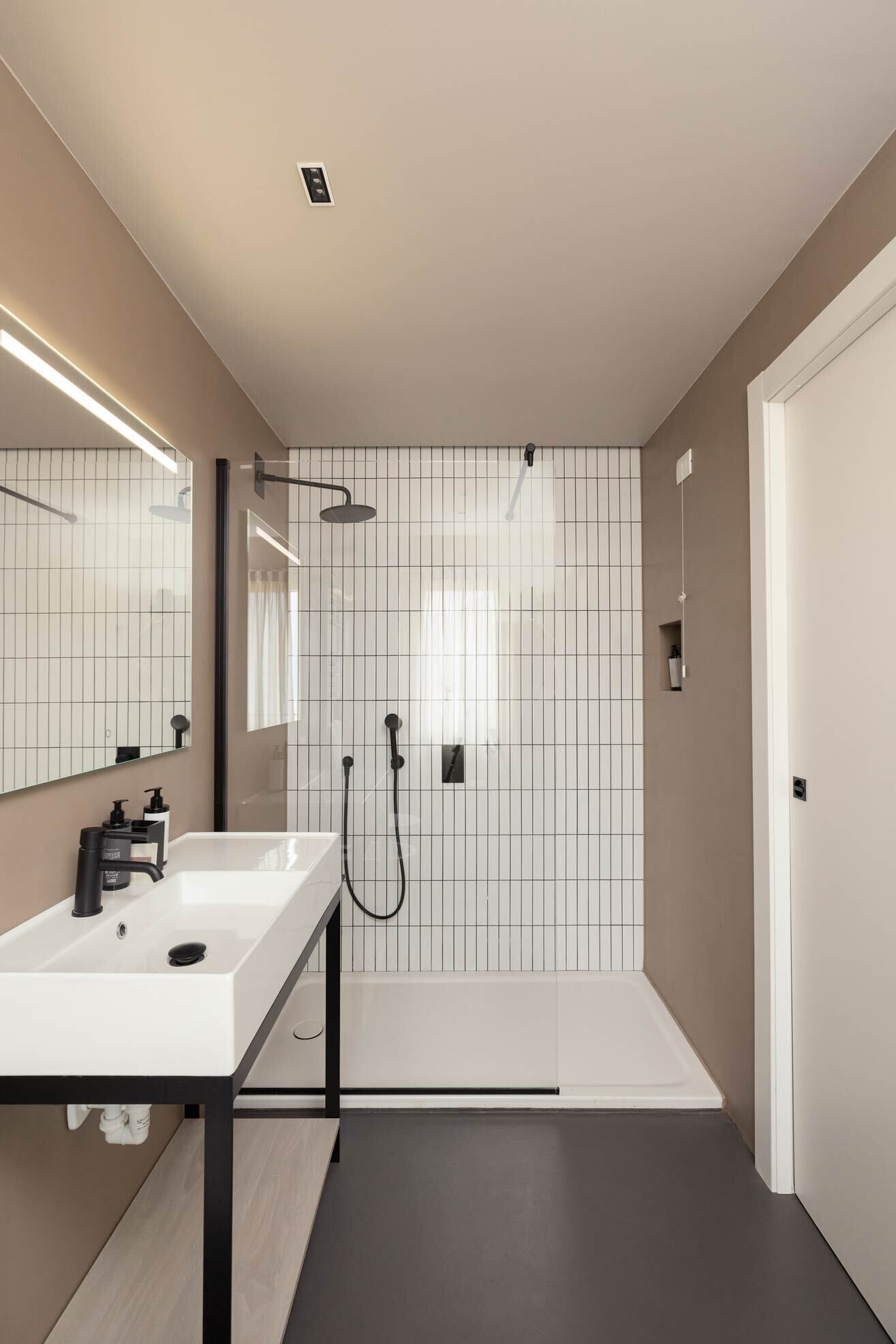 A modern bathroom with a white sink, black faucet, and a shower with a handheld showerhead.