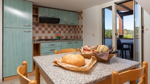 A kitchen with teal cabinets, a granite countertop, and a dining area with a table and chairs. - Residence Villantica (Vieste)