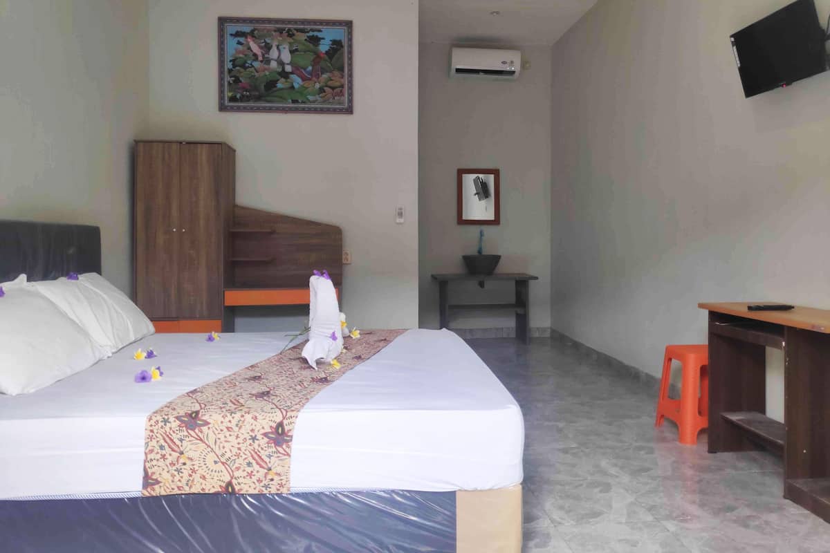 Une chambre d’hôtel comprenant un lit, une armoire en bois, un bureau, une petite table et un téléviseur fixé au mur.