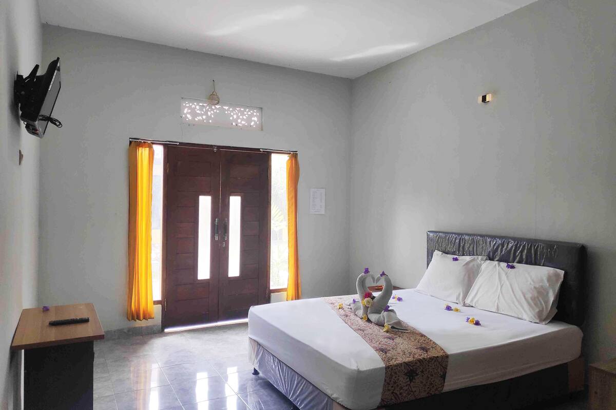 Une chambre d’hôtel avec un lit, un bureau, une chaise, une armoire et une porte.
