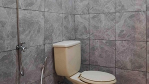 Ein Badezimmer mit Toilette, Dusche und Fliesen.