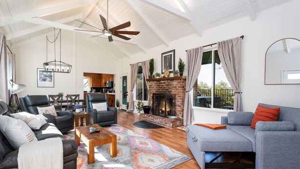 A spacious living room with a fireplace, leather sofas, a coffee table, and a ceiling fan.