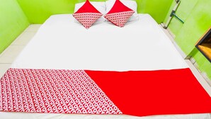 A bed with a white and red bedspread, two red pillows, and a green wall. - Hotel O Wr House Syariah BatamNearEast Coast Park (Batam)