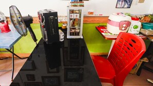 A room with a black table, a red plastic chair, a black fan, a refrigerator, and a microwave. - Hotel O Wr House Syariah BatamNearEast Coast Park (Batam)