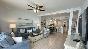 A living room with a grey sofa, a coffee table, and a ceiling fan.