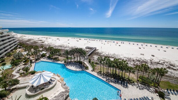 A resort with a large pool, beach, and ocean view.