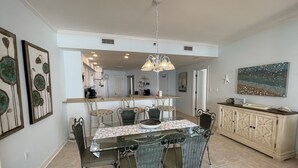 A dining area with a glass table, wicker chairs, and a pendant light.