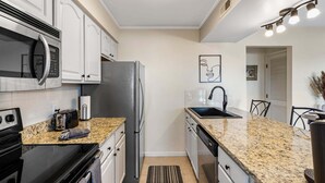 A modern kitchen with granite countertops, stainless steel appliances, and a black faucet. - Modern Luxury Condo with Private Deck, Amazing Views, Near SDC with Free Tickets (Branson)