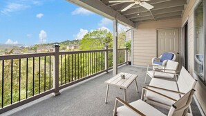 A covered balcony with a ceiling fan, outdoor seating, and a view of a residential area. - Modern Luxury Condo with Private Deck, Amazing Views, Near SDC with Free Tickets (Branson)