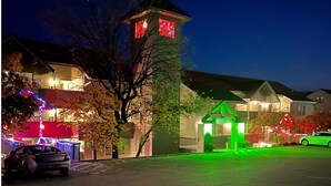 A residential area at night with houses illuminated by various colored lights, a car parked in the foreground, and a small tower-like structure with red lights. - Modern Luxury Condo with Private Deck, Amazing Views, Near SDC with Free Tickets (Branson)