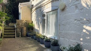 A white building with a window, potted plants, and a stone wall. - Embassy (Weymouth)