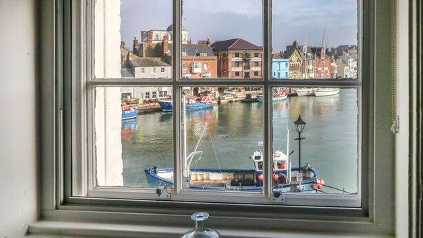A window with a view of a harbor, boats, and buildings. - Embassy (Weymouth)