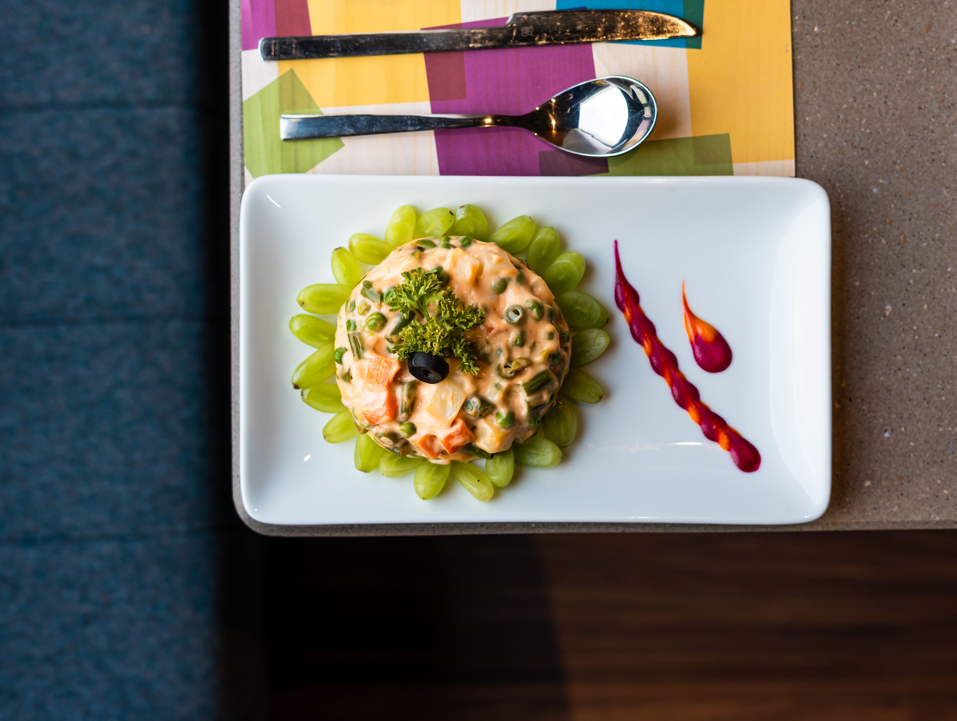 Een witte rechthoekige schaal met een salade op een kleurrijke placemat.