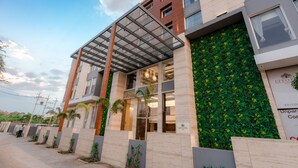 A modern building with a glass entrance, a green wall with yellow flowers, and a sign reading "EFFORT". - Effotel By Sayaji Bhopal (Bhopal)