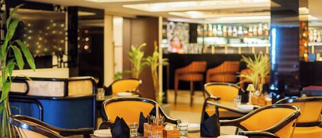 A restaurant with tables and chairs, a bar area, and potted plants.