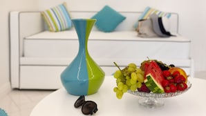 A white sofa with colorful pillows, a blue and green vase, and a fruit bowl on a white table. - Gala Residence Villa Giovanna (Ravello)