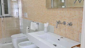 Une salle de bain moderne avec un grand lavabo, deux toilettes, une douche et un miroir.