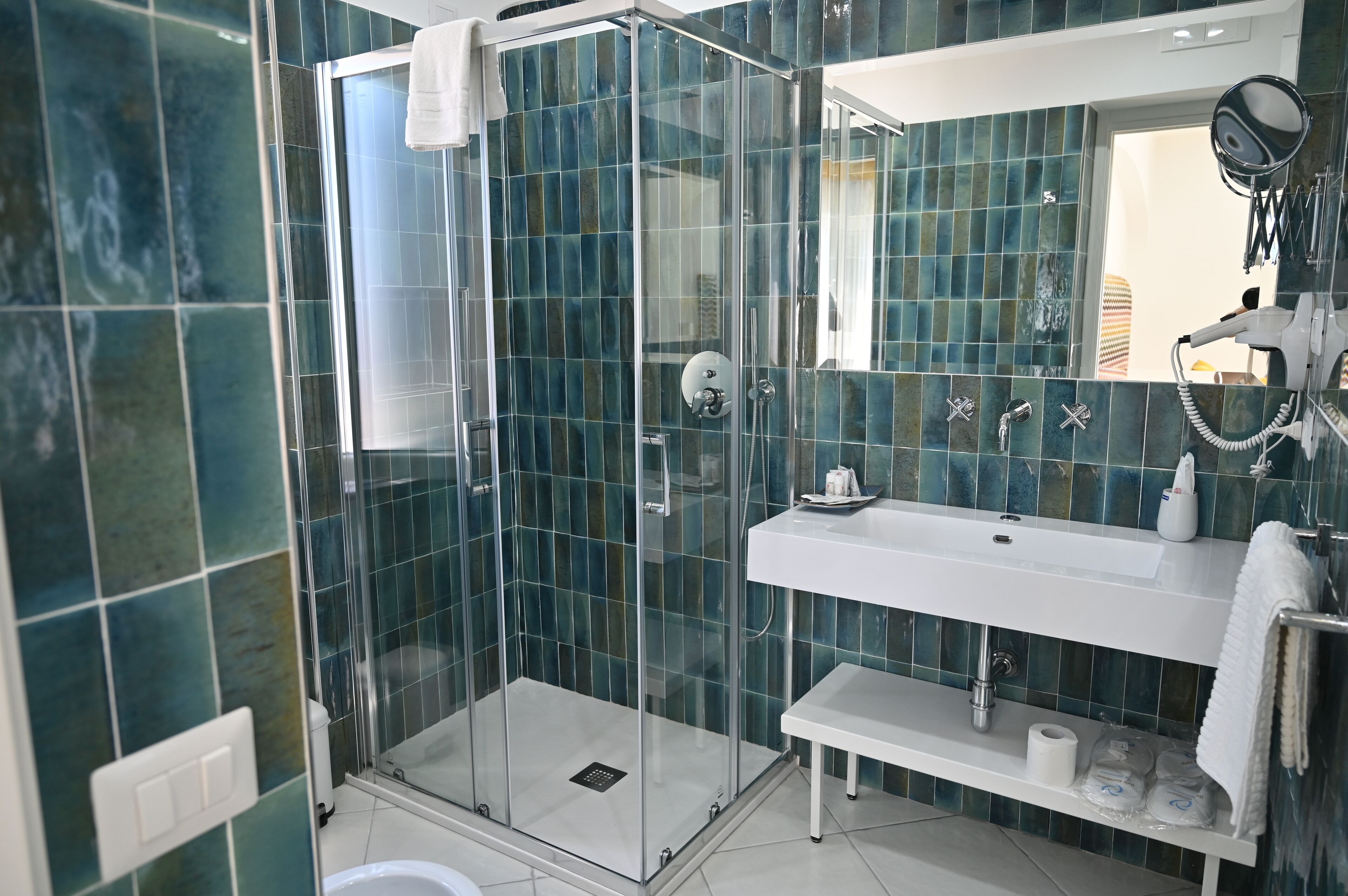 A modern bathroom with a glass shower enclosure, a white sink, and a mirror.