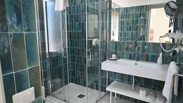 A modern bathroom with a glass shower enclosure, a white sink, and a mirror.