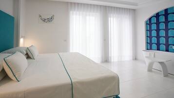 Een moderne hotelkamer met een groot bed, een bureau en uitzicht op zee door een raam met blauw getinte glas.