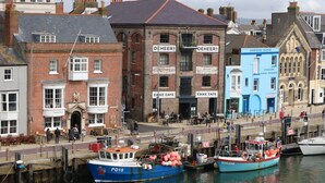 A waterfront area with buildings, including 'Custom House' and 'Ebike Cafe'. Boats are docked along the water.
