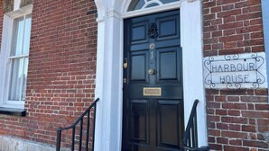 A brick building with a black door and a sign reading 'Harbour House.'