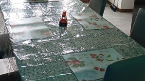 Una zona de menjador amb una taula coberta amb un mantell estampat, dues cadires i un objecte decoratiu sobre la taula.