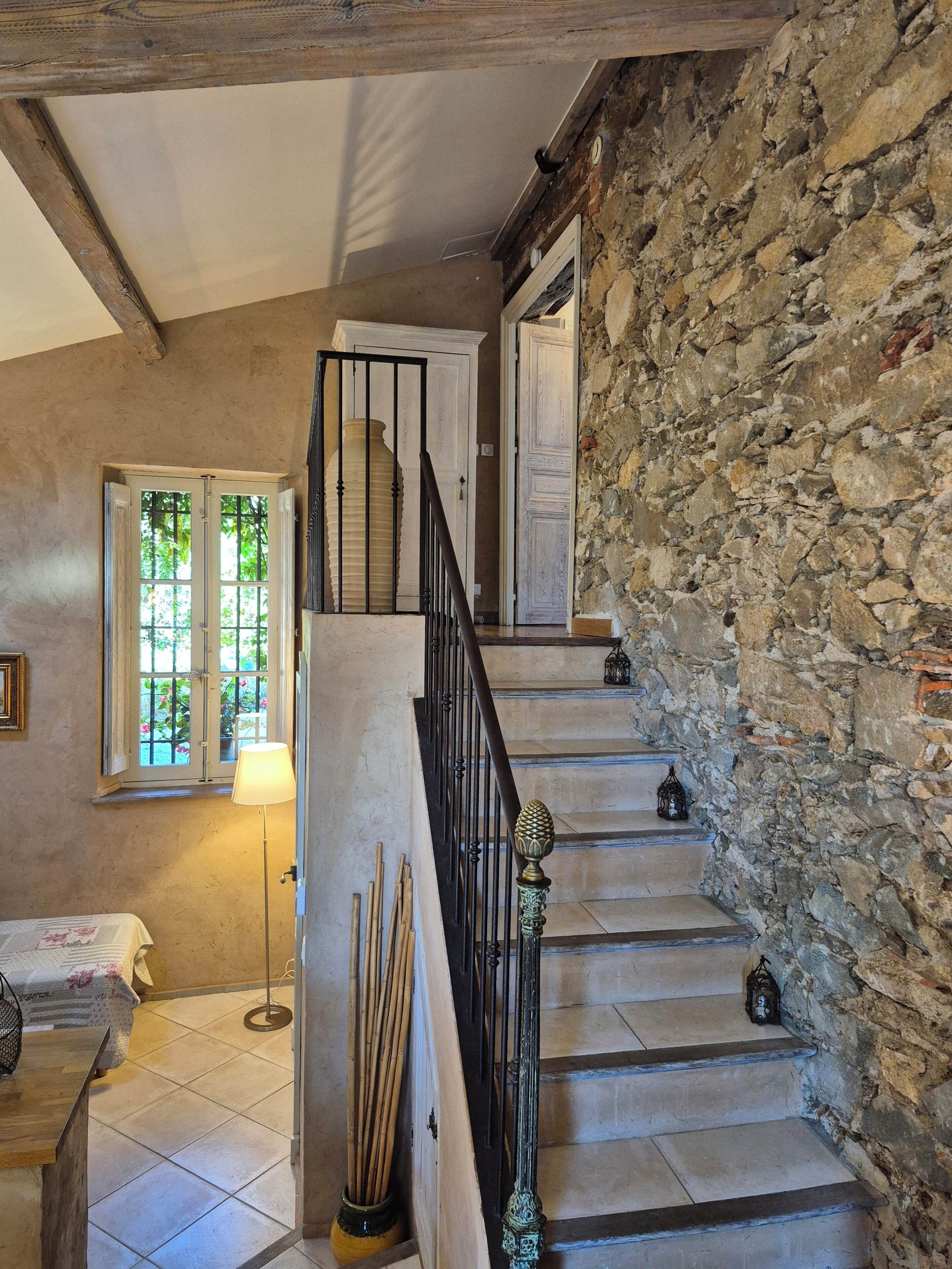 A staircase with stone walls, a wooden floor, and a lamp.