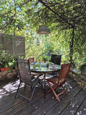 An outdoor dining area with a round table, chairs, and a hanging light fixture. - Charming stone house for 4 rated 5 stars (Grimaud)