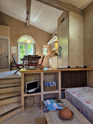A cozy room with a wooden desk, a chair, a bookshelf, a television, and a window with a view of greenery. - Charming stone house for 4 rated 5 stars (Grimaud)