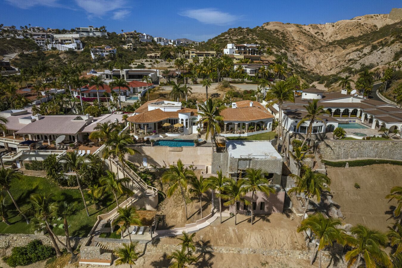 A coastal residential area with multiple houses, a swimming pool, and palm trees.