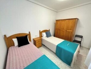 A bedroom with two single beds, a wooden wardrobe, a nightstand, and a chair. - apartment arrecife beyond (Arrecife)