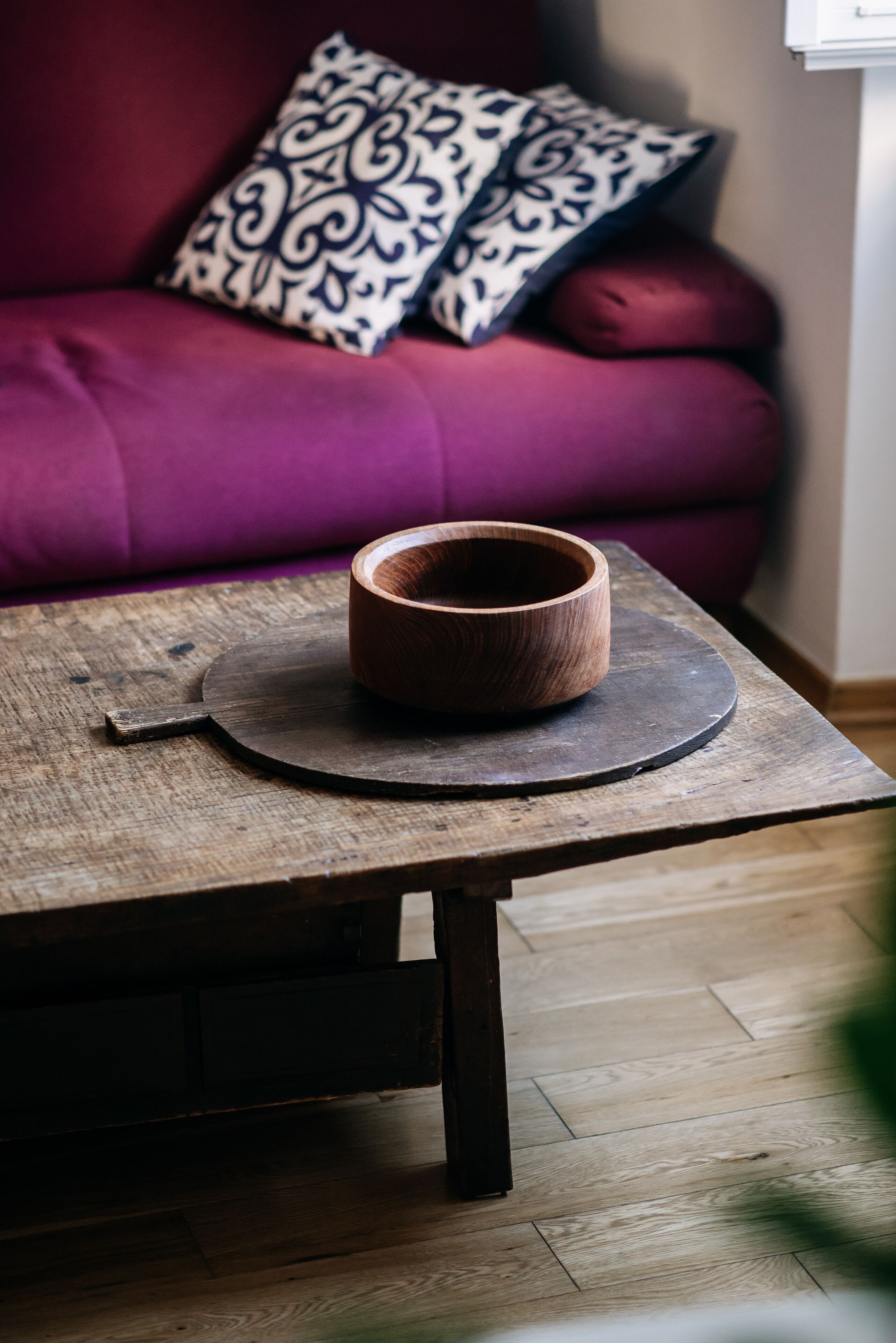A wooden bowl on a round coaster on a rustic wooden table.
