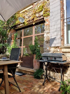 Un patio al aire libre con una parrilla, una mesa con un bol y una silla.