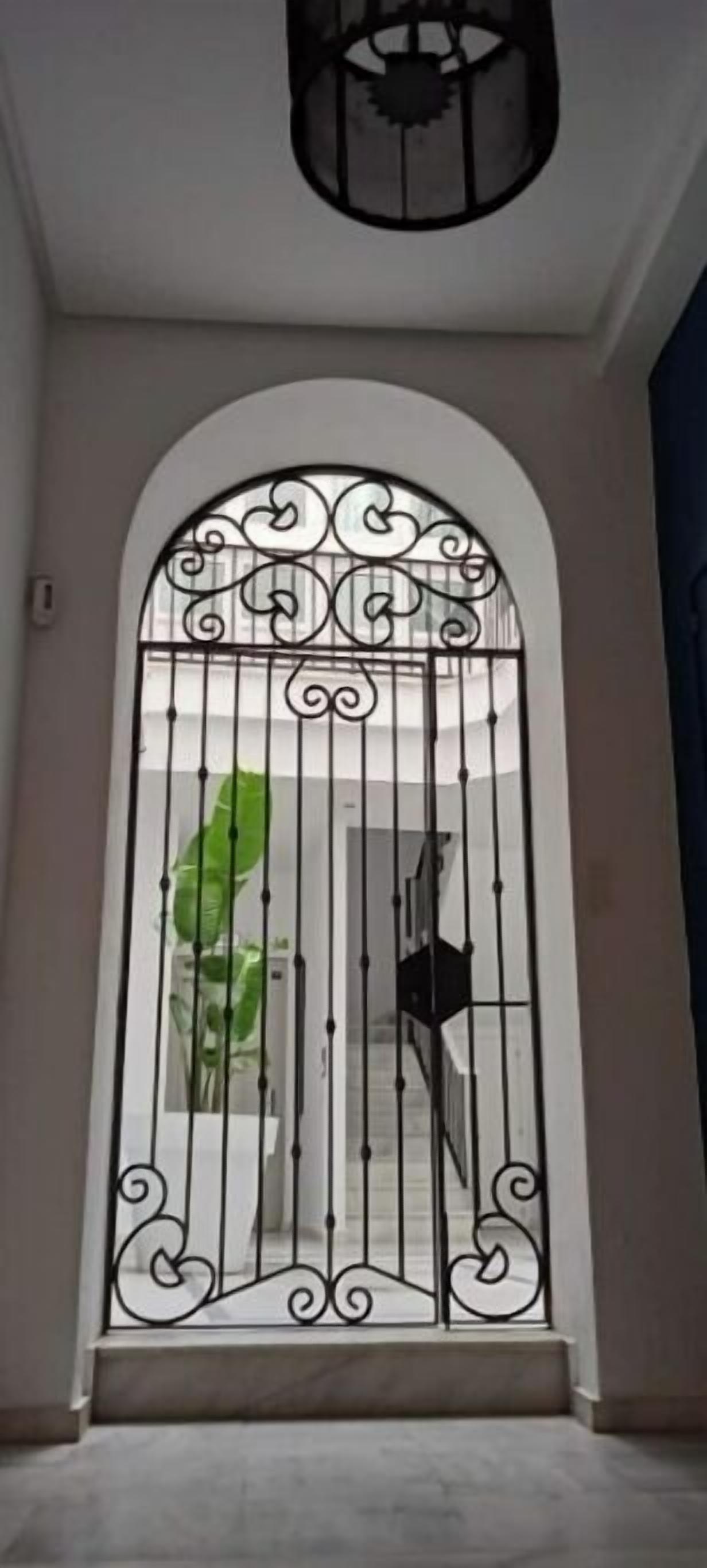 Un gran portal arquejat amb treballs metàl·lics detallats i un panell de vidre.