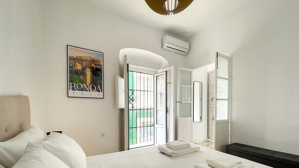 Habitación de hotel con cama, ventana grande con vistas, puerta y unidad de aire acondicionado.