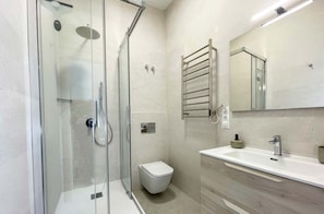 Ein modernes Badezimmer mit Duschkabine, Toilette, Waschbecken mit Spiegel und Handtuchhalter.