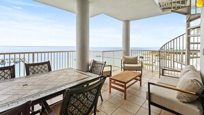 Un balcon avec une table et des chaises, un canapé et une vue sur la mer.