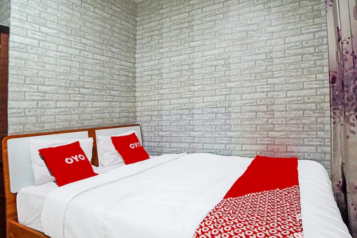 Ein Bett mit weißer Bettwäsche und roten Akzenten, eine Wand mit Ziegelmuster und ein hölzernes Kopfteil.