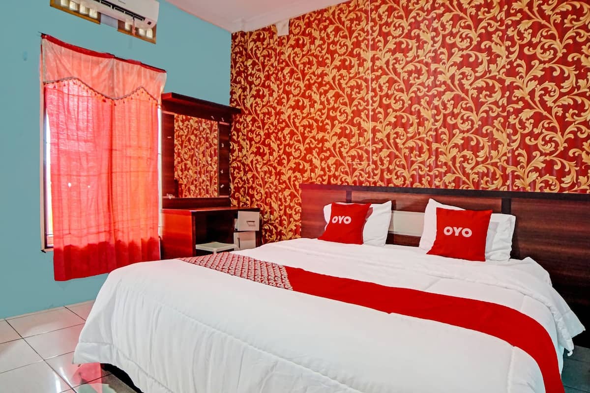 Ein Hotelzimmer mit einem großen Bett, zwei Nachttischen, einem Spiegel und einem Fenster mit roten Vorhängen.