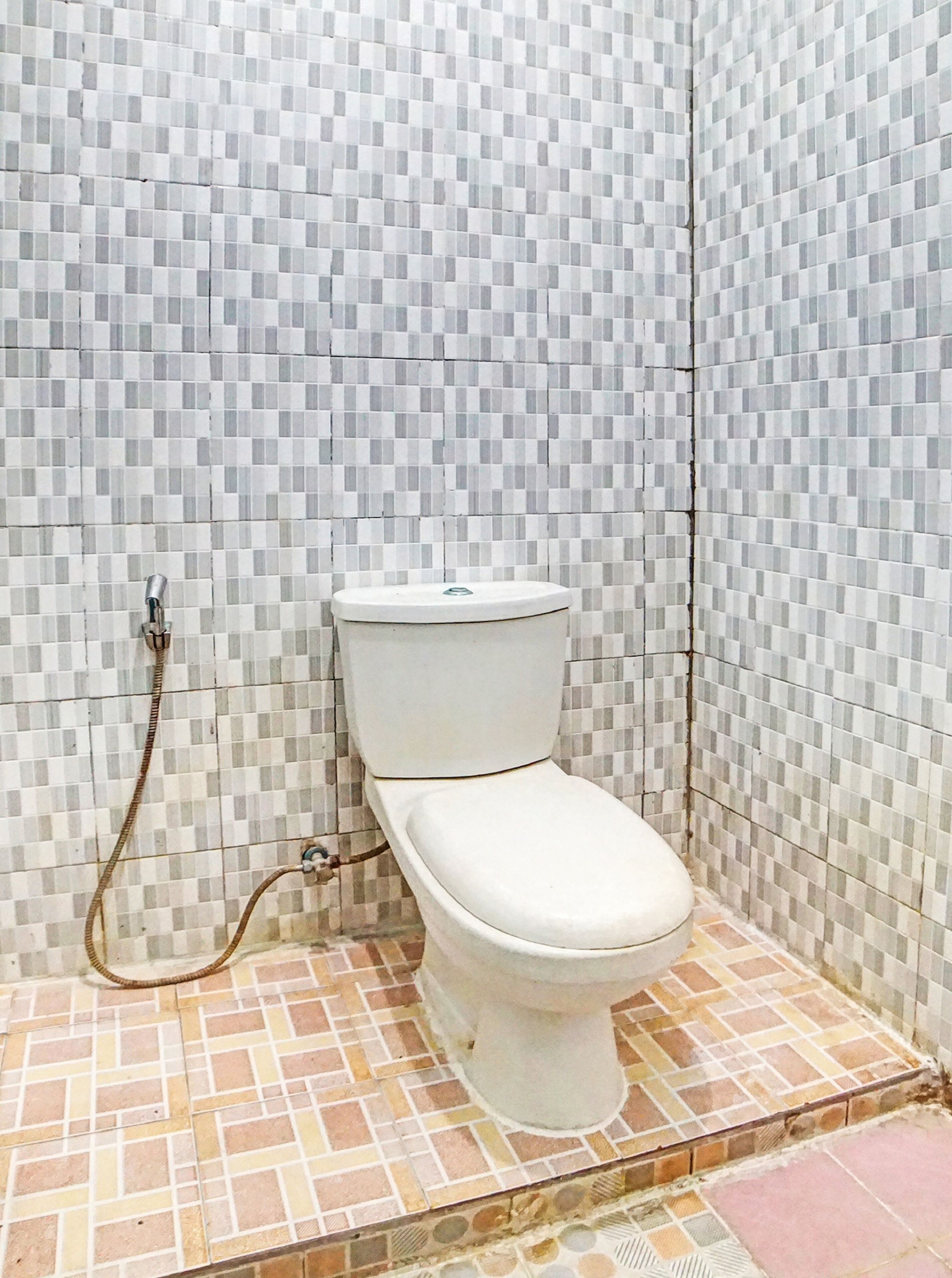 A bathroom with a toilet, tiled walls, and a shower area.