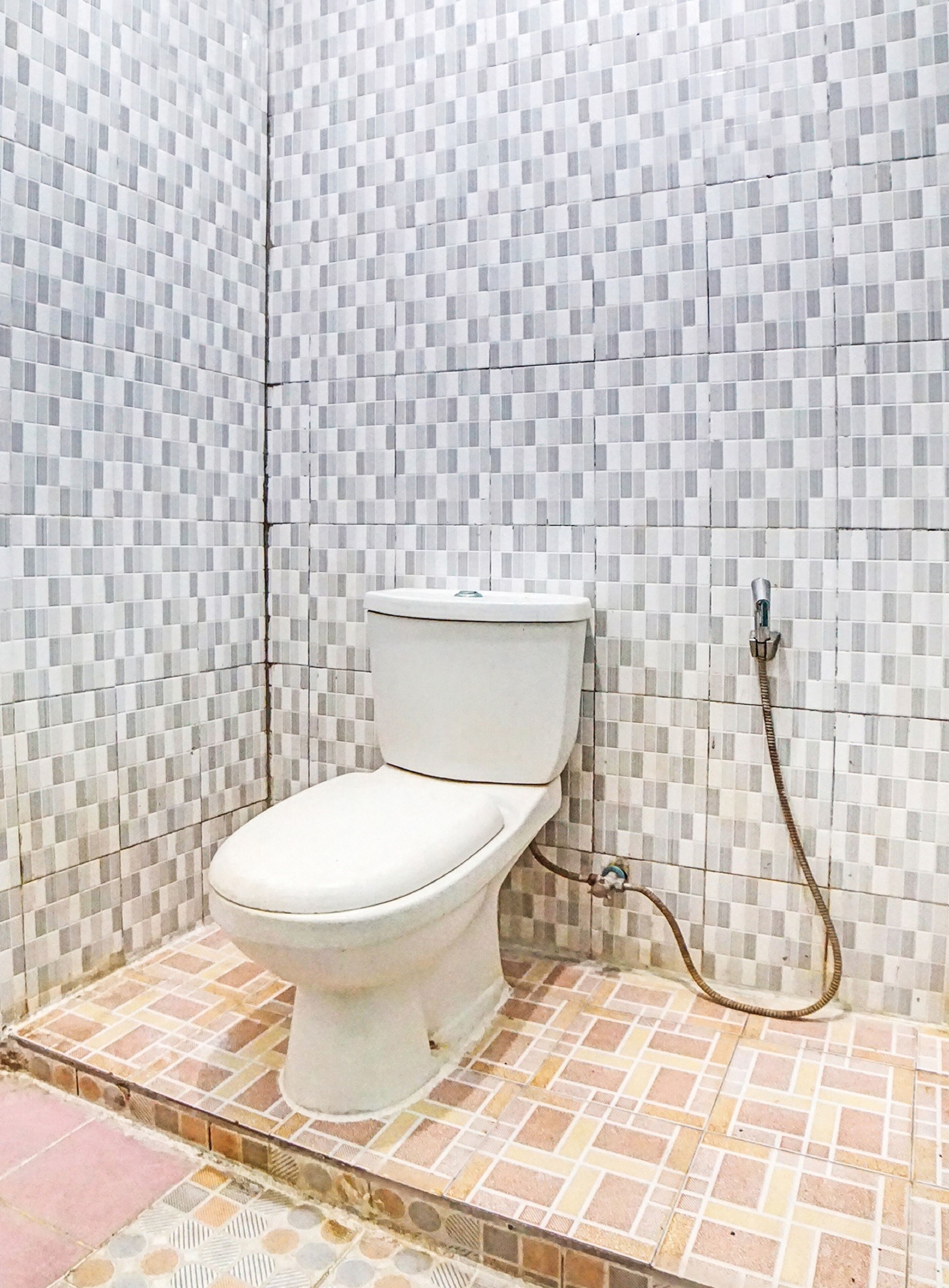 Une salle de bain avec des toilettes, des murs carrelés et un espace douche.