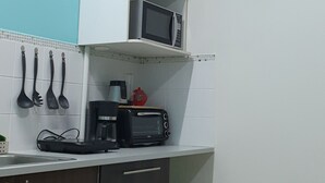 Une cuisine compacte équipée d’un four à micro-ondes, d’un grille-pain et d’une petite poubelle.