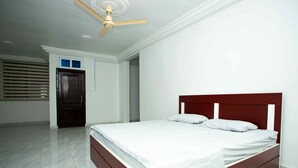A bedroom with a bed, a ceiling fan, and a door. - The Boaz Executive Place (Kumasi)
