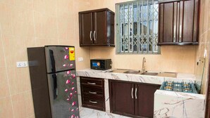 A kitchen with a refrigerator, microwave, sink, and cabinets. - The Boaz Executive Place (Kumasi)