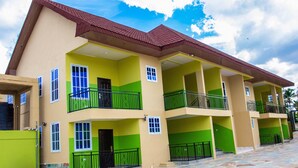 A multi-story building with balconies, a tiled ground floor, and a clear sky. - The Boaz Executive Place (Kumasi)