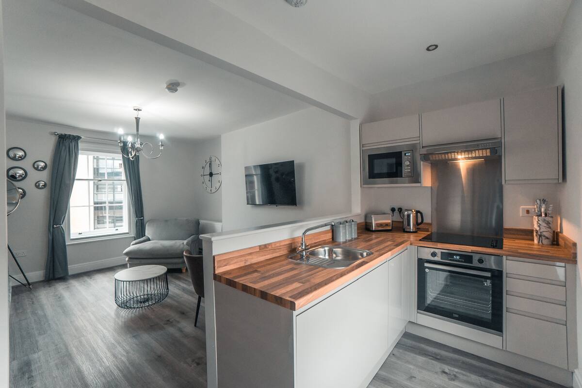 A modern kitchen with a wooden countertop, stainless steel appliances, and a built-in oven.