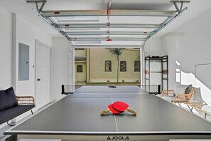 Ein Tischtennistisch mit Netz in einem Zimmer mit Blick auf ein äußeres Gebäude.
