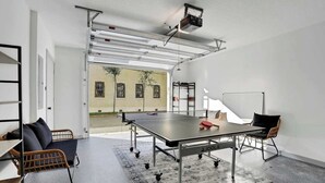 A ping pong table in a modern room with a view of a building outside. - New Construction in Historic Linconville (Saint Augustine)